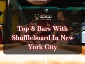 Top 8 Bars With Shuffleboard In New York City - three men playing with a shuffleboard while holding drinks at a bar